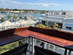 A balcony with a view of a marina, buildings, and a clear sky. - Luxury Living in Cullen Bay (Darwin City)