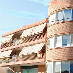 Een gebouw met meerdere verdiepingen, balkons en grote ramen.
