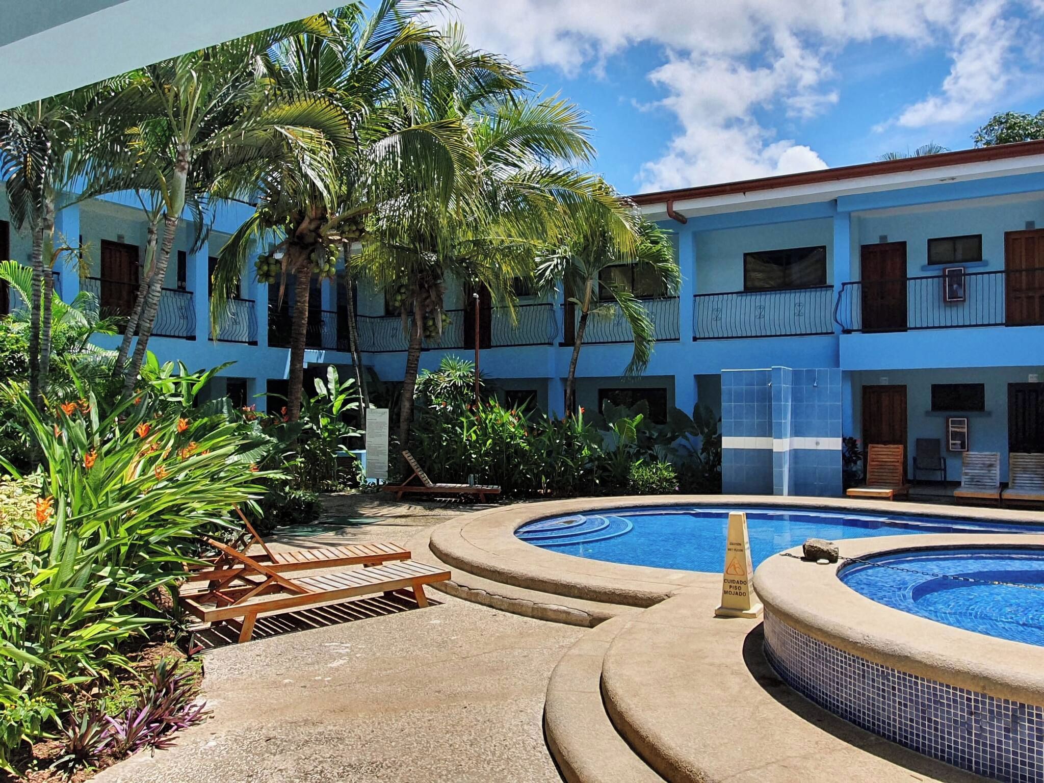 A pool area with a circular hot tub, lounge chairs, and a building with balconies.