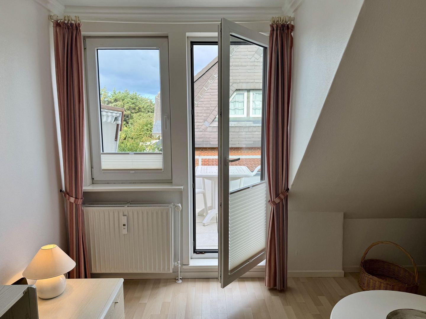 A room with a window, radiator, and a table with a lamp.
