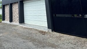 Een modern huis met twee verdiepingen, een garage, een balkon en een trap naar de bovenverdieping.
