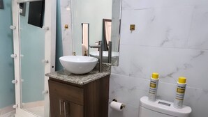 Een badkamer met een wastafel, een spiegel, toilet en twee flessen shampoo.