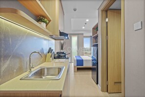A compact kitchen with a sink, stove, and cabinets. - Eslin by Kozystay - Cilandak (South Jakarta)