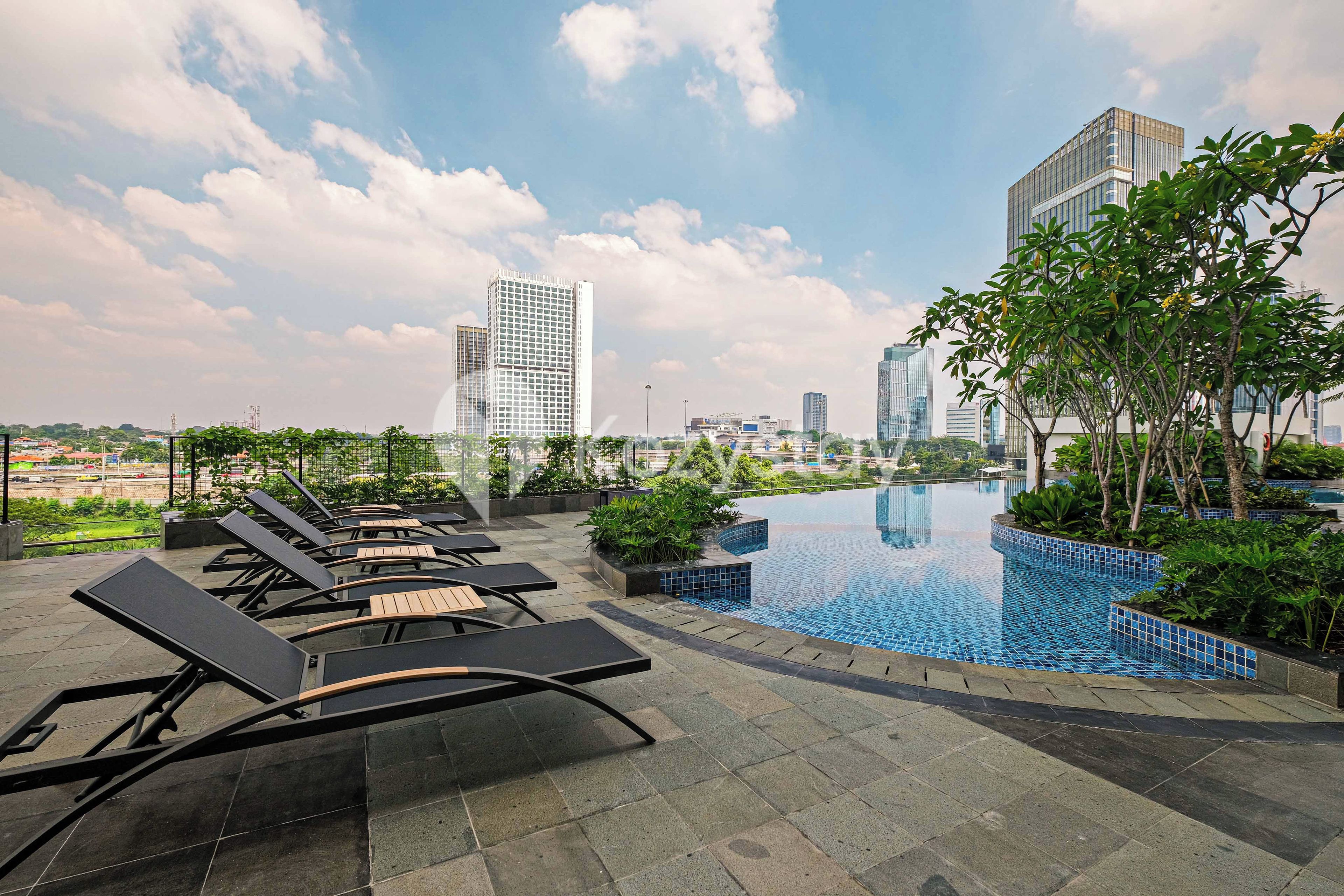 A rooftop pool area with lounge chairs and a view of city buildings.