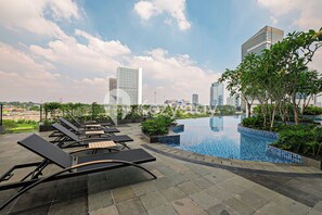 A rooftop pool area with lounge chairs and a view of city buildings. - Eslin by Kozystay - Cilandak (South Jakarta)
