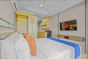 Una camera d'albergo con un letto, una TV, un minibar e il bagno.