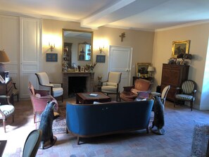 Uma sala de estar tradicional com lareira, várias poltronas, um sofá e um espelho.