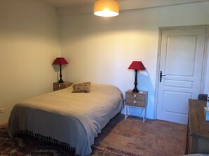 Quarto com cama, duas mesas de cabeceira com luminárias, uma porta e um tapete estampado.