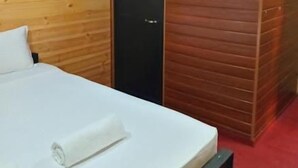 A hotel room with a bed, a door, and an air conditioning unit. - Hiriketiya Budget Stay (Dikwella)