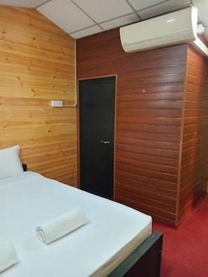 Une chambre d’hôtel avec un lit, une porte et un appareil de climatisation.