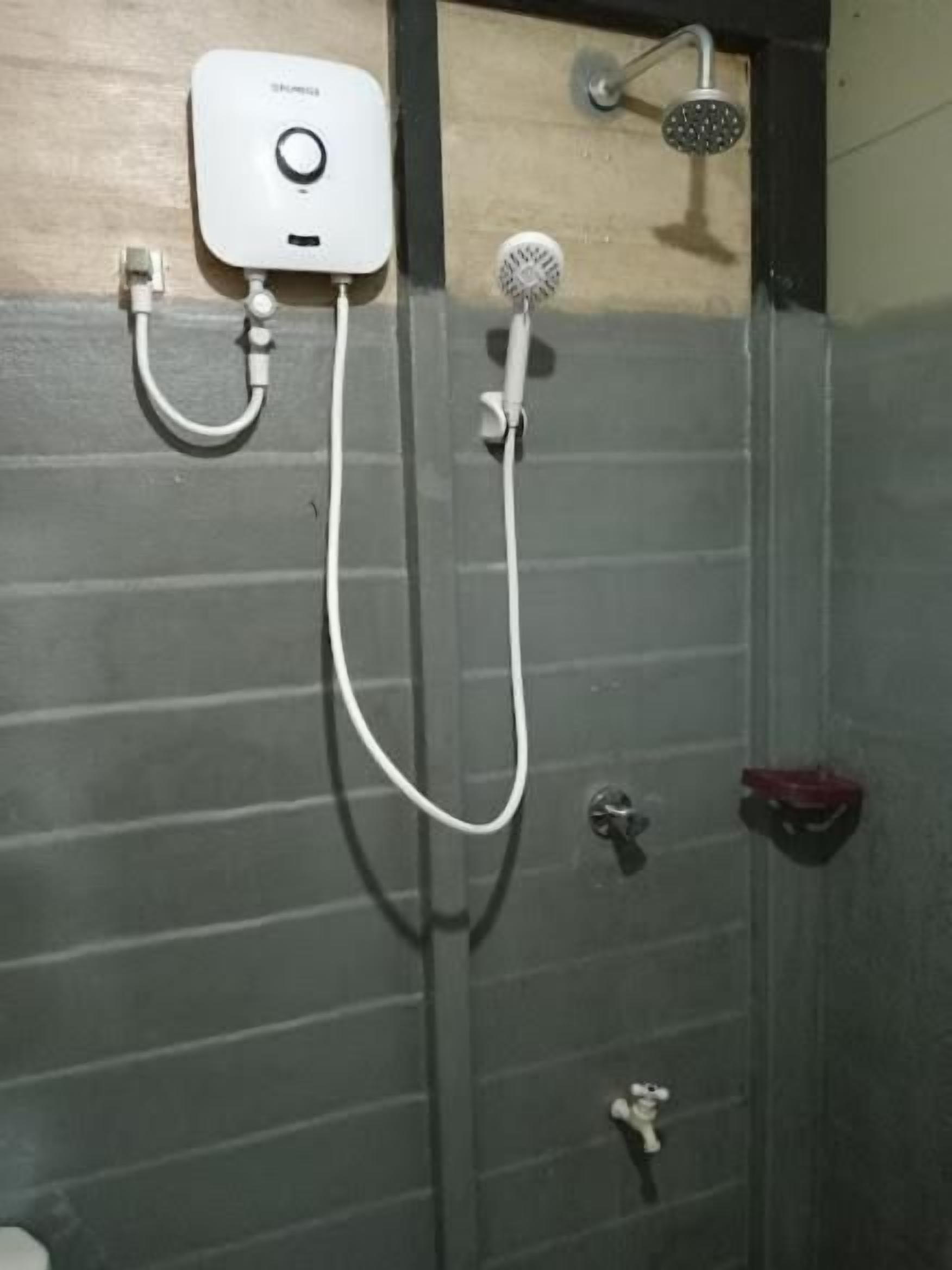 A shower with a handheld showerhead and a wall-mounted faucet.