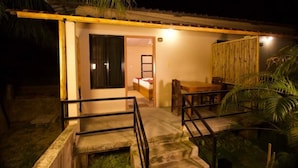 A single-story building with a wooden deck, a staircase leading to a door, and a bed visible inside. - Narayani Vista Riverside Resort  (Kawasoti)
