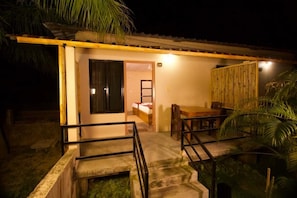 A single-story building with a wooden deck, a staircase leading to a door, and a bed visible inside. - Narayani Vista Riverside Resort  (Kawasoti)