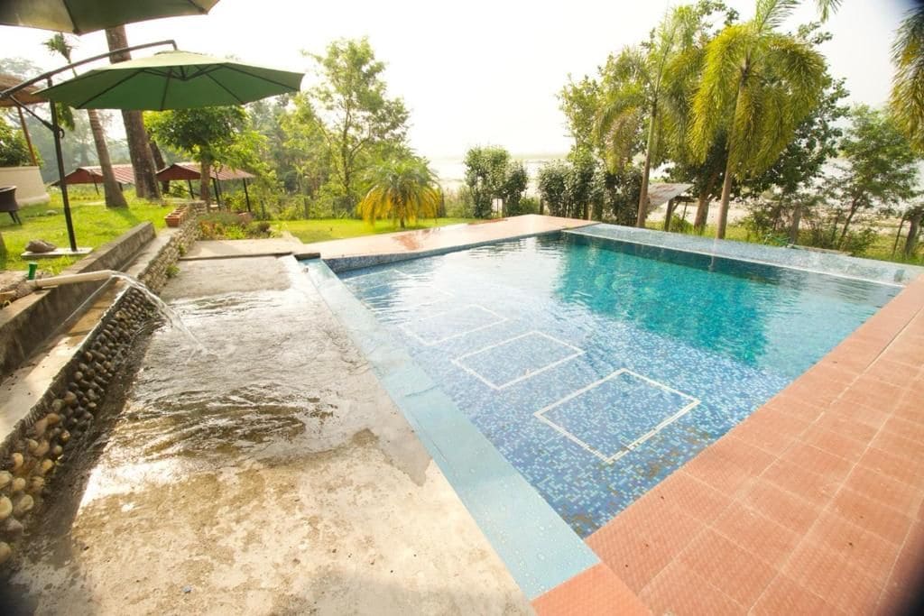 A swimming pool with a tiled edge, surrounded by a stone wall and greenery.