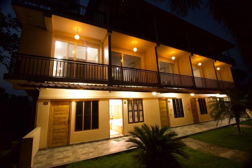 A two-story building with balconies, a front entrance, and a well-lit facade.