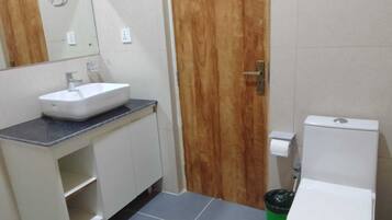 A bathroom with a white sink, wooden door, and a white toilet.