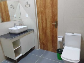 A bathroom with a white sink, wooden door, and a white toilet.