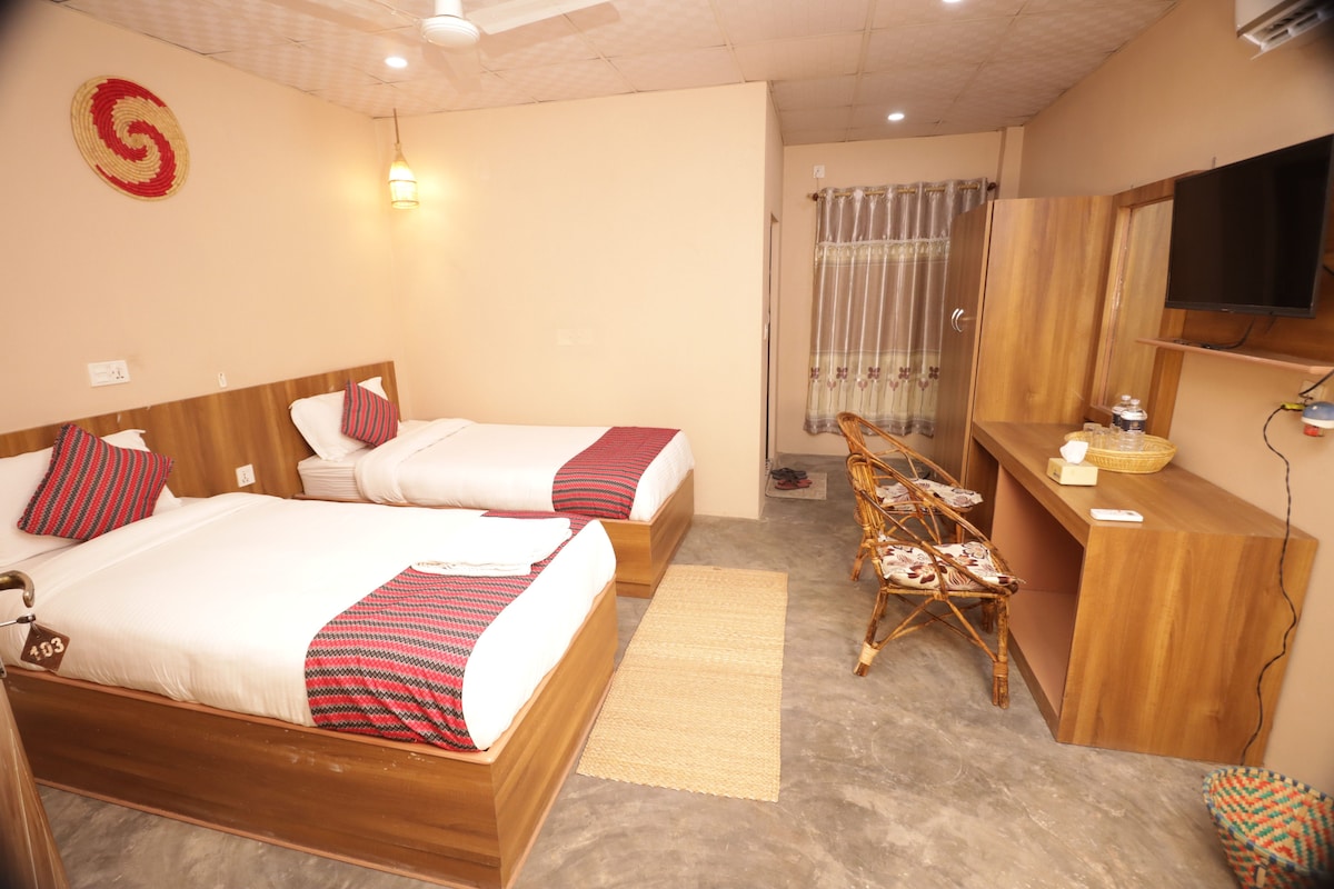 A hotel room with two beds, a desk, a chair, a television, and a window with curtains.