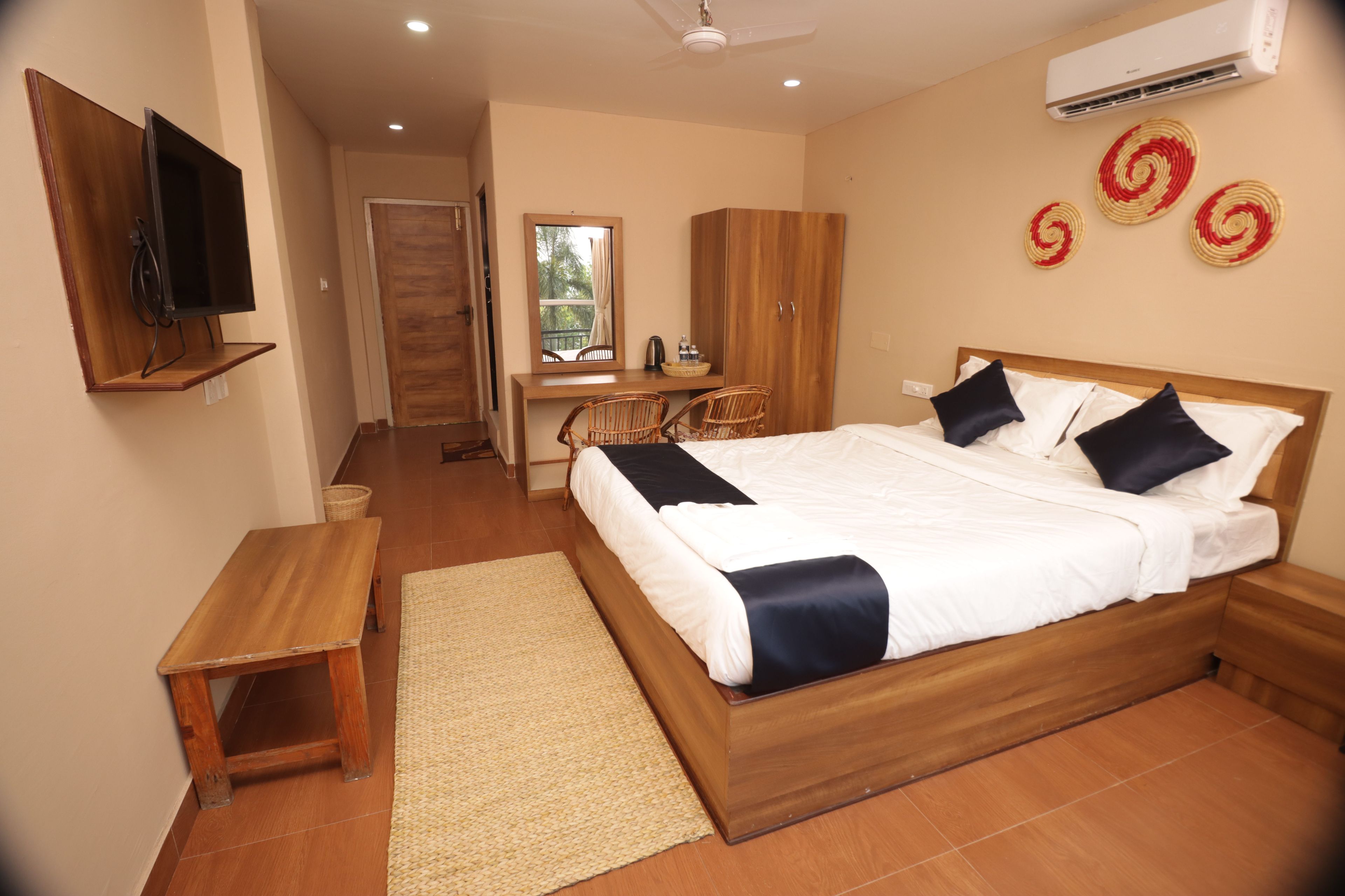 A bedroom with a bed, bedside tables, a desk, and an air conditioning unit.