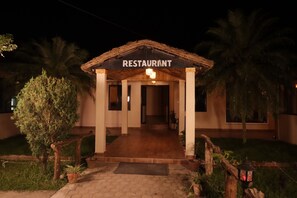 A restaurant with a thatched roof entrance, a paved walkway, and potted plants. - Narayani Vista - Near Chitwan National Park (Kawasoti)
