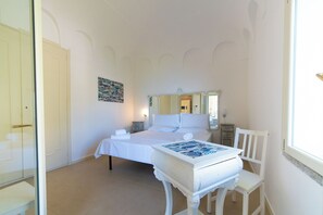 A hotel room with a bed, a bedside table, a chair, a dresser, a mirror, and a painting on the wall. - Solemar Sicilia - Villa Emmax (Santa Flavia)
