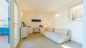 En minimalistisk stue med sofa, et lille bord og et billede hængende på væggen.