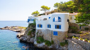 A coastal building with multiple balconies, stone walls, and a view of the sea. - Solemar Sicilia - Villa Emmax (Santa Flavia)