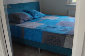 A single bed with a headboard, a window to the right, and a radiator below. - Bungalow in Ballum with swimming pool (Ballum)