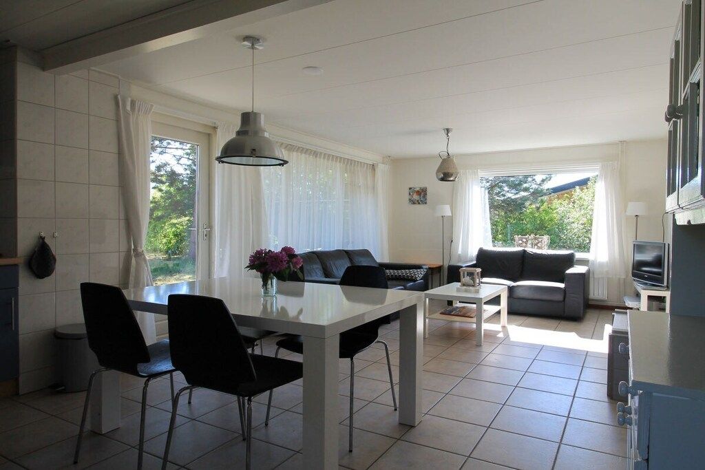 Un espacio de estar moderno con comedor, dos sofás, televisor y zona de cocina.