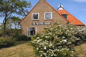 A brick building with a sign reading 'DE WITTE REEP' and a red-tiled roof. - Holiday home with 2 bedrooms (Hollum Ameland)