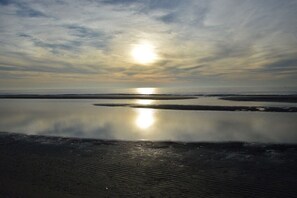 A beach with calm water reflecting the sky and sun. - Holiday home with 2 bedrooms (Hollum Ameland)