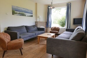 A living room with a sofa, armchair, and coffee table. - Holiday home with 2 bedrooms (Hollum Ameland)