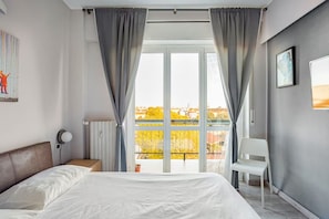 A bedroom with a bed, a chair, a radiator, and a window with curtains. - Bright Apartment with a Canal-View Balcony (Milano)