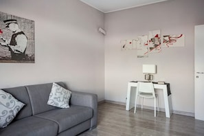 A modern living room with a grey sofa, a white desk, and abstract art on the wall. - Bright Apartment with a Canal-View Balcony (Milano)