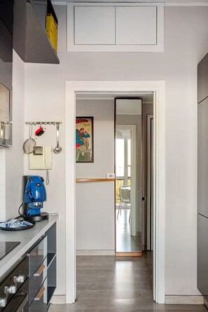 A modern kitchen with a coffee machine, a phone, and a poster on the wall. - Bright Apartment with a Canal-View Balcony (Milano)
