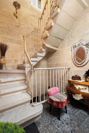 A staircase with ornate metal railings, a decorative mirror, and a floral-patterned chair. - Maltese Home w/ Balcony - Valletta (Valletta)