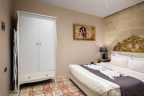 A bedroom with a bed, a wardrobe, a nightstand, a lamp, and a painting on the wall. - Maltese Home w/ Balcony - Valletta (Valletta)