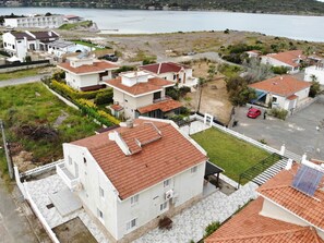 A residential area with houses featuring red-tiled roofs, a paved driveway, and a view of a body of water. - Beachfront Big Villa (Çeşme)