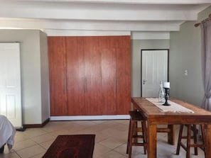 A dining area with a wooden table and chairs, a rug, and a door in the background. - Skilpadvlei Accommodation (Velddrif)