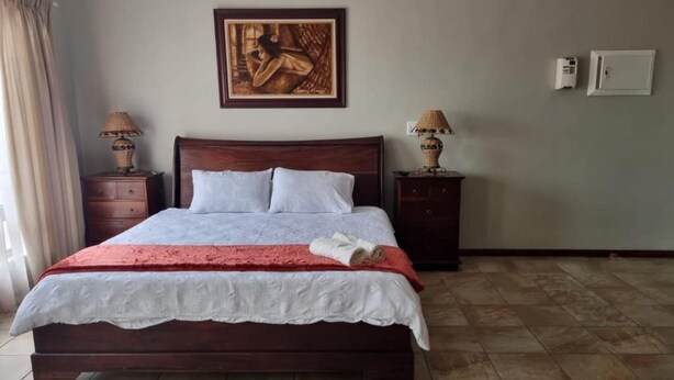 Un dormitorio con una cama grande, dos mesitas de noche, un equipo de aire acondicionado de pared y un cuadro sobre la cama.