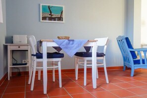 A dining area with a table and chairs, a small cabinet, and a framed picture on the wall. - Holiday apartment in Tangermünde with Wi-Fi (Tangermünde)