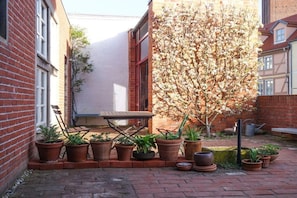 A brick building with a small patio area containing potted plants and a wooden table. - Lady of the Lake||Tangermünde (Tangermünde)