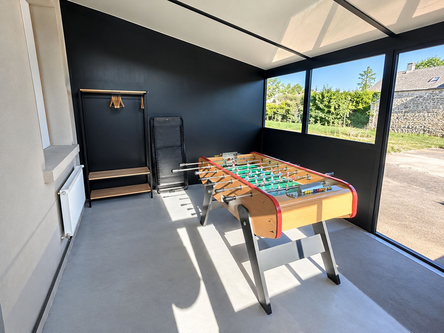 A foosball table in a room with a view of greenery outside.