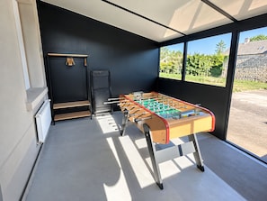A foosball table in a room with a view of greenery outside.