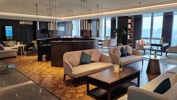 A modern hotel lobby with sofas, a reception desk, and large windows offering a city view.