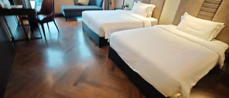 Habitación de hotel con dos camas, un escritorio, una silla y vistas a la ciudad.