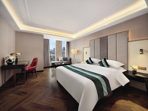 Una habitación de hotel con una cama grande, un escritorio, una silla y vistas a la ciudad.
