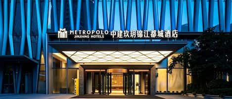 Entrada moderna de hotel com fachada de vidro e placa da Metropole Jinjiang Hotels.