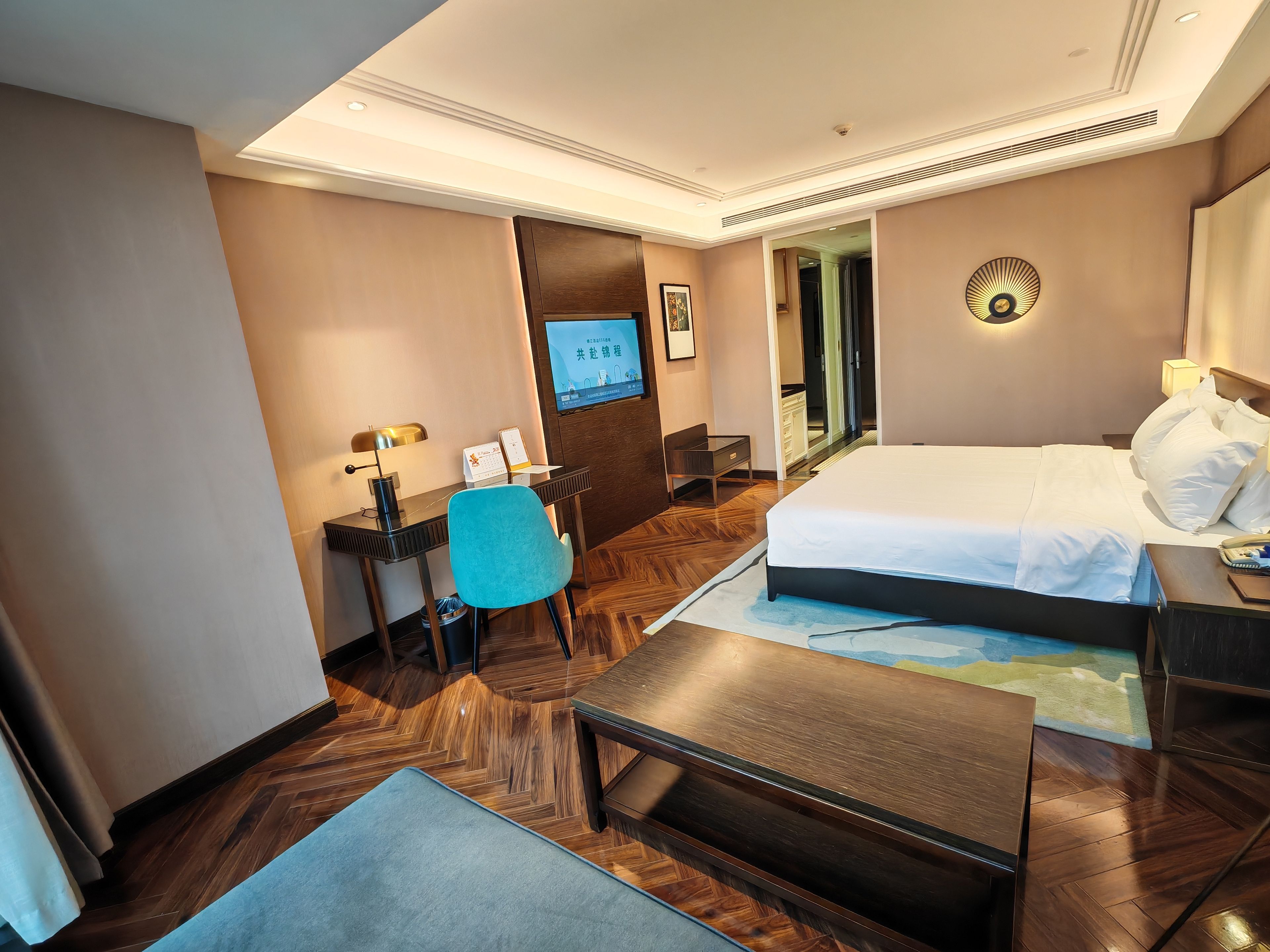 A hotel room with a bed, desk, chair, and a television.