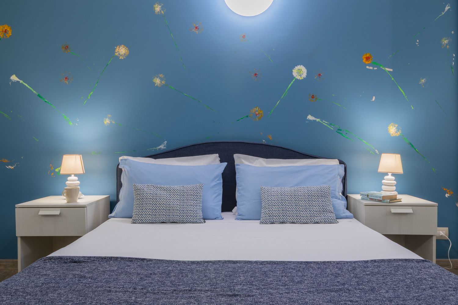 Ein Schlafzimmer mit einem Bett, zwei Nachttischen und einer Wand mit floralen Wandstickern.
